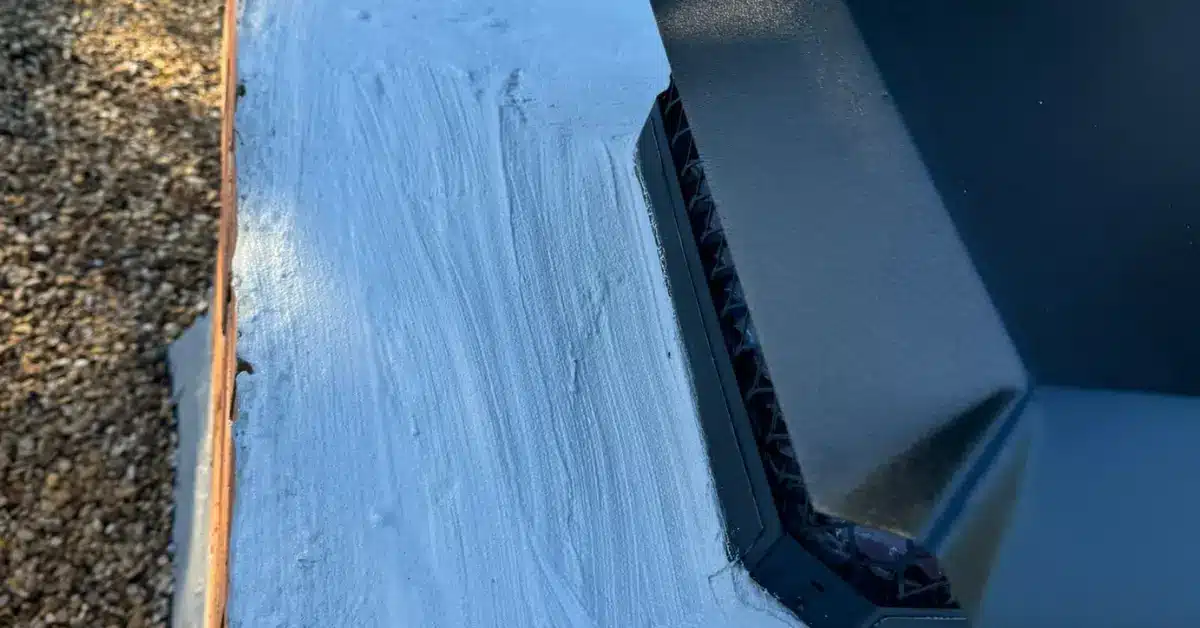 Wet sealant applied around metal chimney flashing on a roof, showing fresh coating by Chimney Professionals.