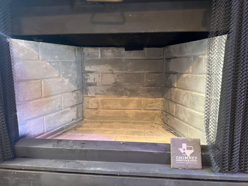 Clean fireplace firebox after inspection, documenting conditions following a chimney leak evaluation.