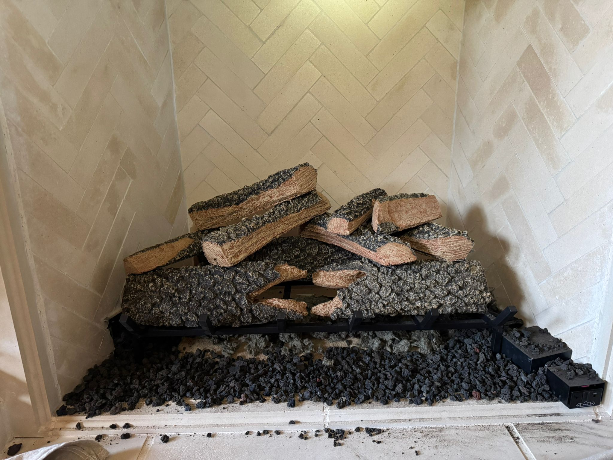 Gas fireplace logs and media inside the firebox, often removed during repairs related to a chimney leak.
