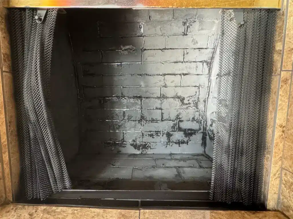 Cleaned brick fireplace interior with dark finish after using a chimney brush.
