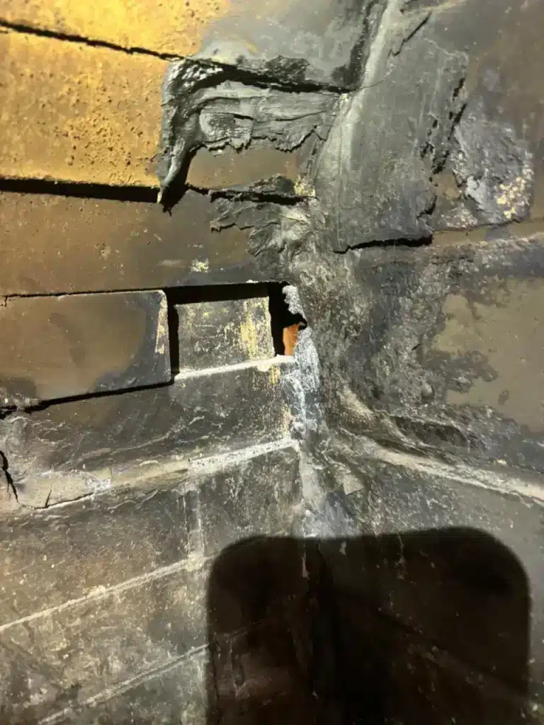 Damaged masonry chimney interior with cracked mortar joints and creosote buildup needing chimney repair.