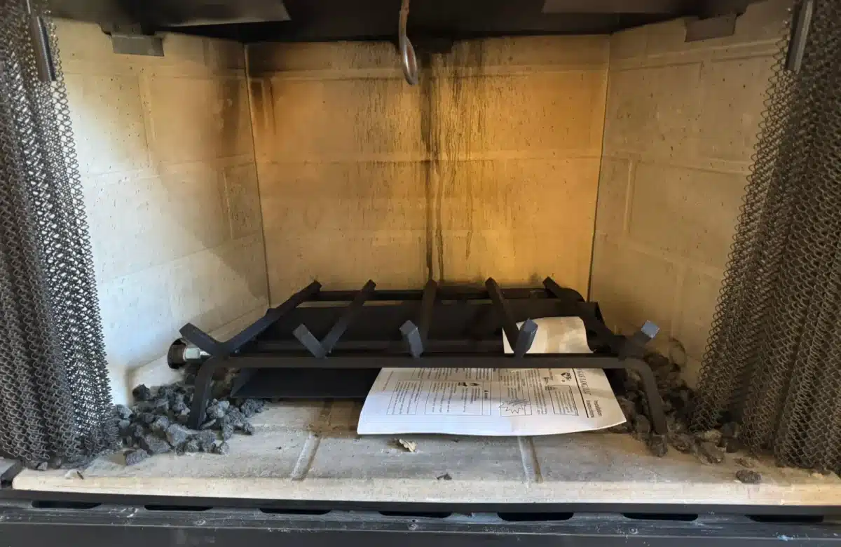 Fireplace interior with soot-stained firebox and metal grate, highlighting potential fireplace safety concerns.